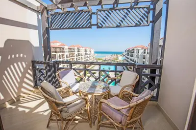 a balcony with chairs and a table and a view of the ocean at Premium sea view 2 bedrooms 2 bathrooms apartment located within Gravity Hotel & Aquapark Hurghada in Hurghada