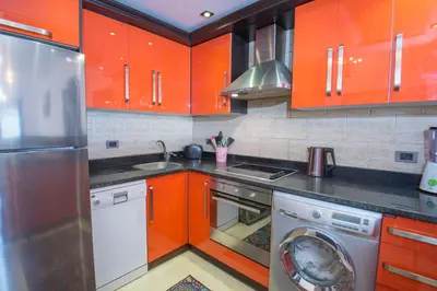 a kitchen with orange cabinets and a washing machine at Premium sea view 2 bedrooms 2 bathrooms apartment located within Gravity Hotel & Aquapark Hurghada in Hurghada