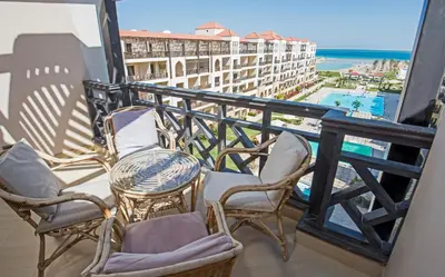 a balcony with chairs and a table and a view of the ocean at Premium sea view 2 bedrooms 2 bathrooms apartment located within Gravity Hotel & Aquapark Hurghada in Hurghada
