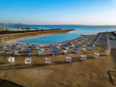a beach with blue and white umbrellas and the ocean at Premium sea view 2 bedrooms 2 bathrooms apartment located within Gravity Hotel & Aquapark Hurghada in Hurghada