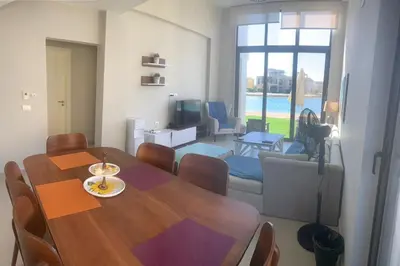 a dining room with a table and a living room at Tawila, 4 Bedroom Villa, Brand new, directly on a lagoon in Hurghada