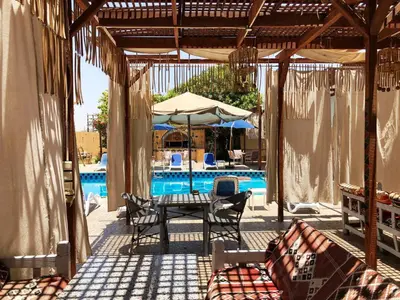 a patio with a table and chairs and a pool at Nile Compound in Luxor