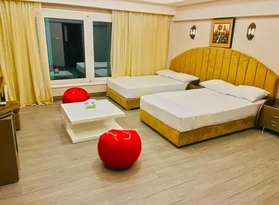 a hotel room with two beds and two red ottoman at Luxury Seafront Pool Villa - 3 Stories & Roof floor - All Master Bedrooms in Hurghada