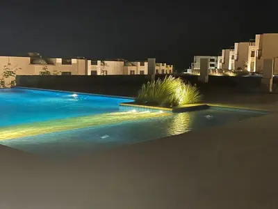 a swimming pool at night with buildings in the background at Villa for you on your own in Makadi Heights, Hurghada, Read Sea, Egypt in Hurghada