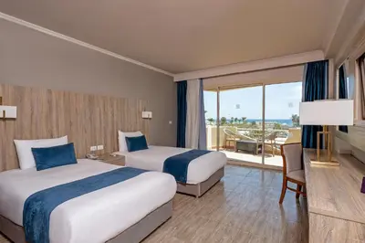 a hotel room with two beds and a balcony at Seven Seas Jolie Bay - Ultra All Inclusive in Hurghada