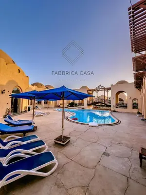 a pool with chairs and umbrellas in a courtyard at Beautiful 1 bedroom apartment in Quseir