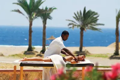 a man is giving a woman a massage at the beach at Bliss Nada Beach Resort in Coraya Bay