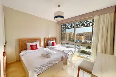 two beds in a room with a large window at Homestyle 3BR Penthouse Pool & Beach View in Hurghada