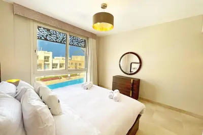 a bedroom with a bed and a window with a pool at Homestyle 3BR Penthouse Pool & Beach View in Hurghada