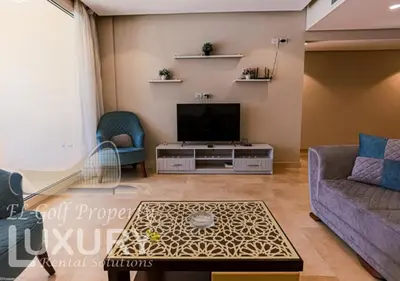 a living room with a tv and a couch and a table at Mangarov-2BR. M1-6b-12 in Hurghada