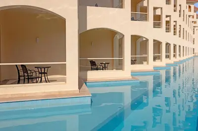 a pool with chairs and tables next to a building at Xanadu Makadi Bay - High Class All Inclusive in Hurghada