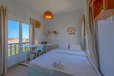 a white bedroom with a bed and a window at Sunny 2 Bedroom + Private Roof Terrace Lagoon View in Hurghada