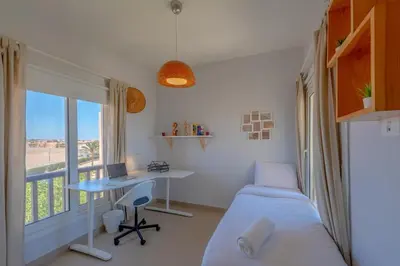 a bedroom with a bed and a desk and a window at Sunny 2 Bedroom + Private Roof Terrace Lagoon View in Hurghada