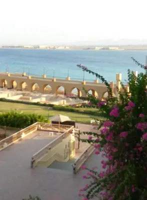 a view of a building with the ocean in the background at VIVA Andalouse luxury family suite, private beach & pool, NO ORFI in Hurghada