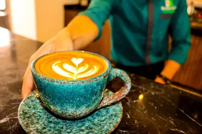 a person holding a blue cup of coffee on a table at Imperial Resort Hurghada in Hurghada