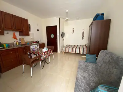a living room with a table and chairs and a kitchen at Чудесная студия в комплексе с бассейном рядом с бесплатным пляжем in Hurghada