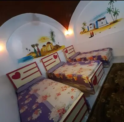 a bedroom with two beds and paintings on the walls at Aziza House in Aswan
