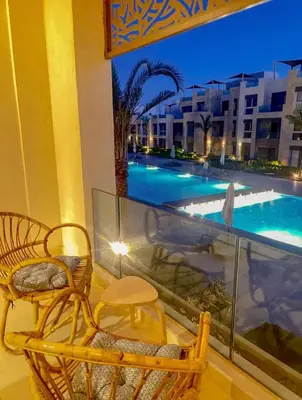 a balcony with a chair and a swimming pool at Mangroovy Gouna 1 BR apartment in Hurghada