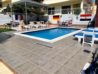 a swimming pool with chairs and a table and a patio at Luxor Oasis Guest House in Luxor