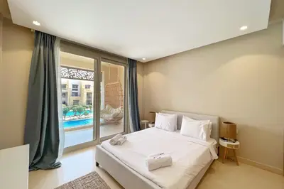 a bedroom with a white bed and a large window at Boho Mint 1 BDR Mangroovy Pool & Sea View in Hurghada
