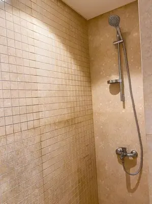 a shower in a bathroom with a tiled wall at Lovely 1 Bedroom apt. At Mangroovy residence with free access to the Beach and Pools in Hurghada