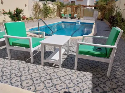 two chairs and a table next to a pool at Jasmine villa in Hurghada