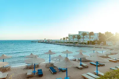 a beach with chairs and umbrellas and the ocean at Royal Star Beach Resort in Hurghada