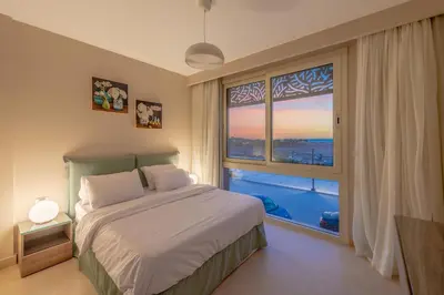 a bedroom with a bed and a large window at Mangroovy 2 Bedroom Sea View Apartment, Pool & Beach in Hurghada