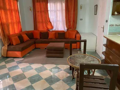 a living room with an orange couch and a table at PORTO HILL in Hurghada