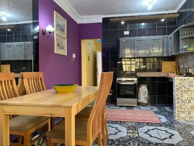 a kitchen with a wooden table and chairs and purple walls at PORTO HILL in Hurghada