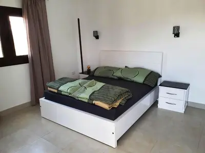 a bedroom with a bed with a white frame and green sheets at CASA LOKO Guest House in Luxor