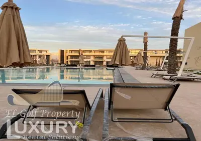 a pool with chairs and umbrellas in front of a hotel at G-Cribs 2 Bed Rooms in Hurghada