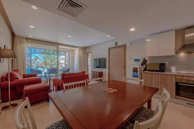 a kitchen and living room with a wooden table and chairs at Elegant 2-Bedroom Apartment in Mangroovy, Pool & Beach in Hurghada