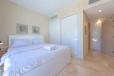 a white bedroom with a large bed and a sliding glass door at Elegant 2-Bedroom Apartment in Mangroovy, Pool & Beach in Hurghada