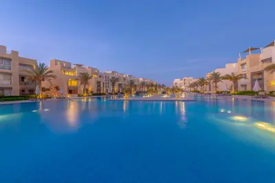 a large swimming pool with palm trees and buildings at Elegant 2-Bedroom Apartment in Mangroovy, Pool & Beach in Hurghada