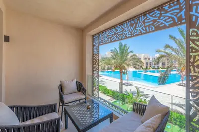 a room with a balcony with a view of the pool at Elegant 2-Bedroom Apartment in Mangroovy, Pool & Beach in Hurghada