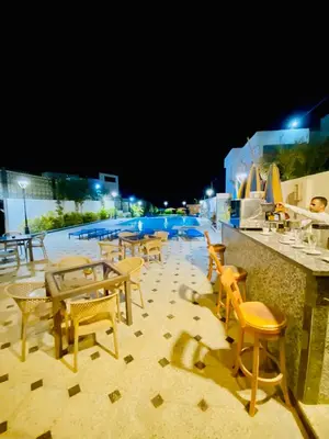 a group of tables and chairs next to a swimming pool at night at Tiba Rose hurghada in Hurghada