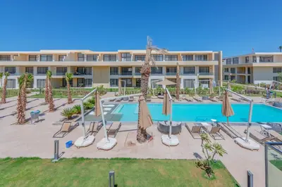 an apartment complex with a swimming pool with umbrellas at Boho-Chic Studio Apartment in G-Cribs, Pool View in Hurghada