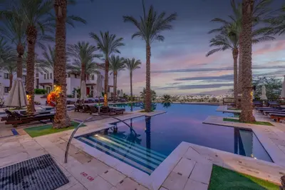 a resort pool with palm trees and tables at Classy 1-Bedroom Apartment in Ancient Sands with Pool View in Hurghada