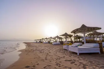 a row of umbrellas and beds on a beach at Stayr Somabay - Bay Life Home Rentals in Hurghada