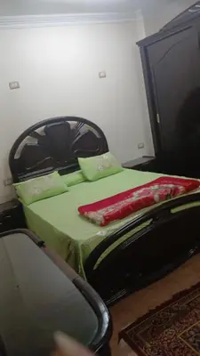 a bedroom with a green bed and a chair at Luxor in Luxor