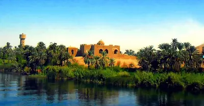 a building next to a body of water with palm trees at Luxor in Luxor