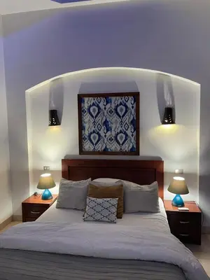 a bedroom with a large bed with two lamps on it at Sabina 1br apartment Lagoon view with shared pool By BFG Beit Fel Gouna in Hurghada