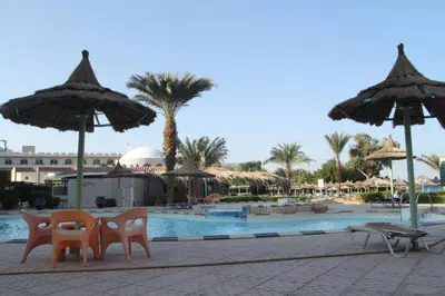 a group of chairs and umbrellas next to a pool at Dexon Roma Hotel in Hurghada