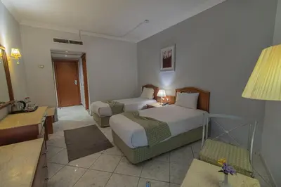 a hotel room with two beds and a table at Dexon Roma Hotel in Hurghada