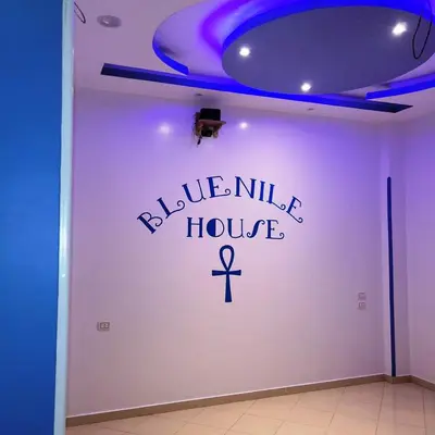 a room with a white wall with the words blue nile house at Blue Nile House in Luxor