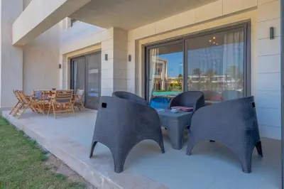 a patio with chairs and a table and a dining room at Cozy 2-Bedroom Apartment in G-Cribs, El Gouna. Terrace & Pool in Hurghada