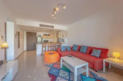 a living room with a red couch and a table at Cozy 2-Bedroom Apartment in G-Cribs, El Gouna. Terrace & Pool in Hurghada