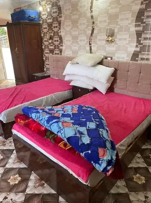 two beds in a room with red sheets at Nubian Dreams Guest House in Aswan