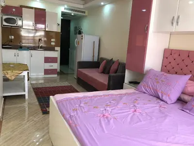 a living room with a pink bed and a kitchen at Cecelia in Hurghada